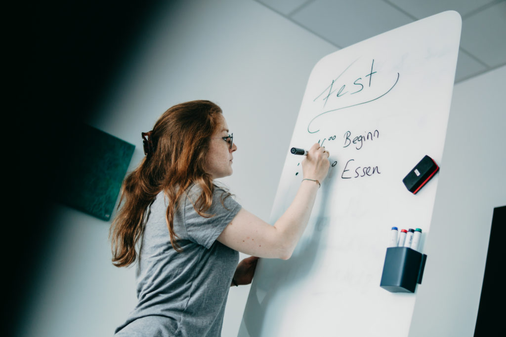 Junge Dame steht am Flipchart und schreibt im nova:med Konferenzraum