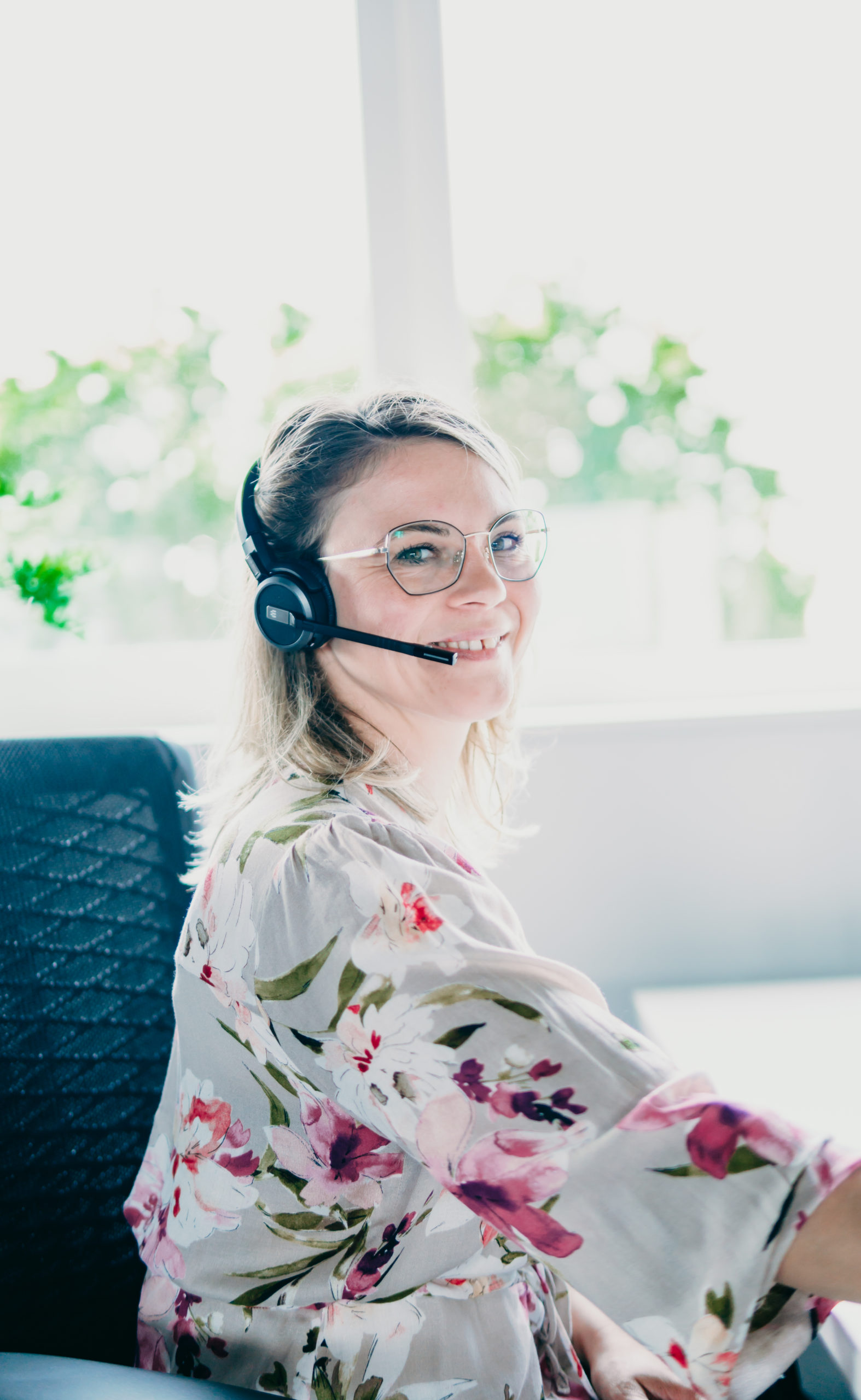 nova:med Support Mitarbeiterin trägt ein Headset und lacht