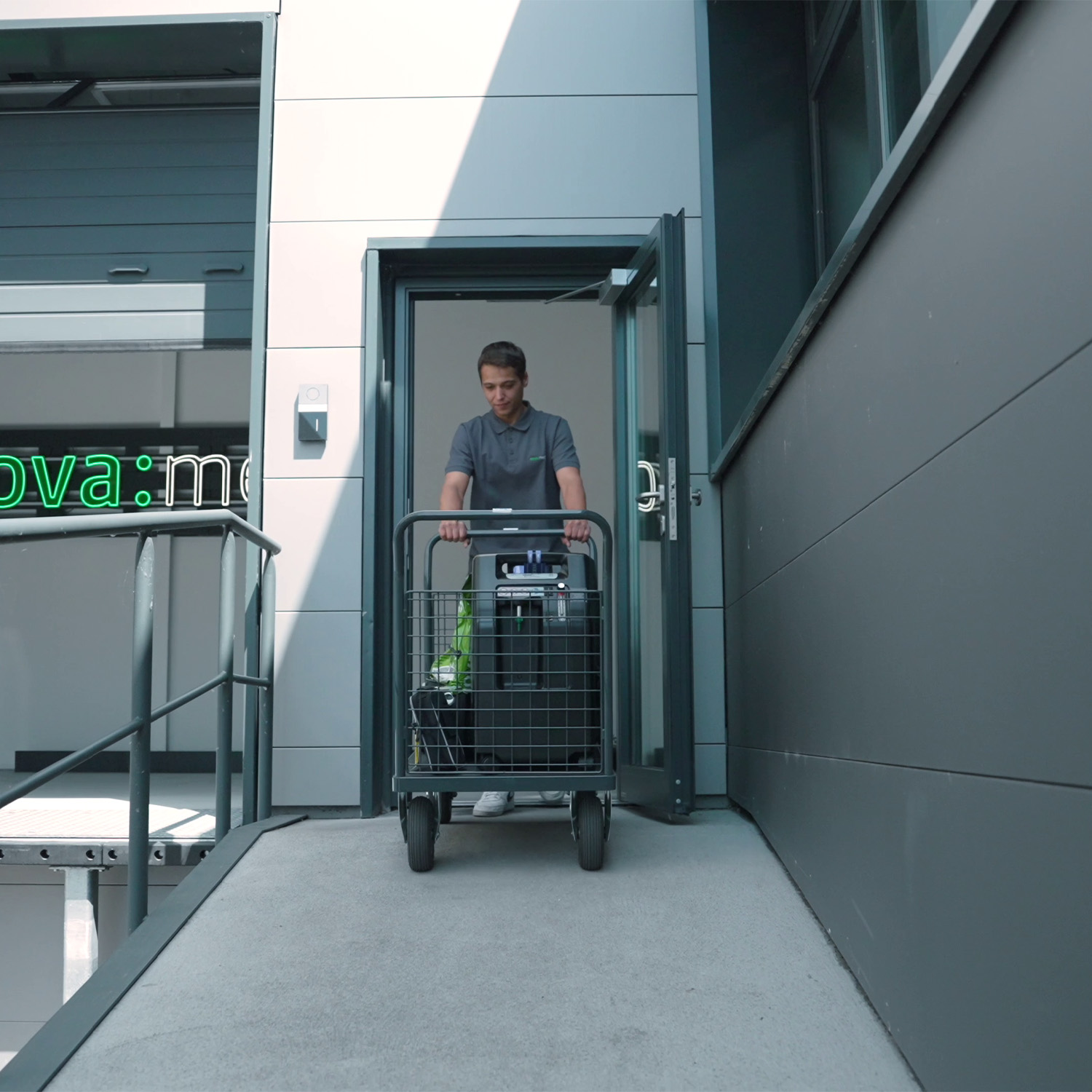 Ein Mitarbeiter von nova:med transportiert einen Sauerstoffkonzentrator auf einem Rollwagen